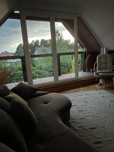 un soggiorno con divano e ampie finestre di Dom w (Między) lesie a Zwierzewo