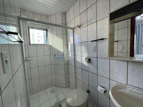 a bathroom with a sink and a toilet and a mirror at Aconchegante apartamento no centro em Balneário Camboriú SC in Balneário Camboriú