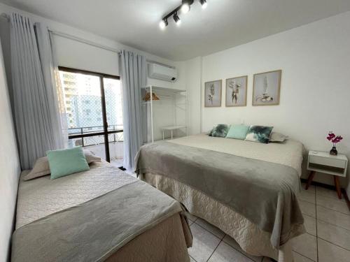1 dormitorio con 2 camas y balcón en Aconchegante apartamento no centro em Balneário Camboriú SC en Balneario Camboriú