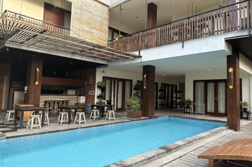 an outdoor pool with tables and chairs next to a building at The Paving Villa in Canggu