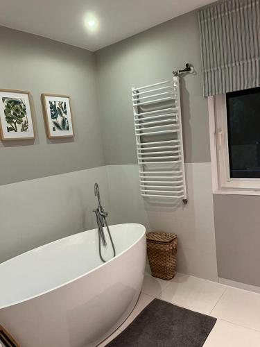 a white bath tub in a bathroom with a window at Dom w (Między) lesie in Zwierzewo