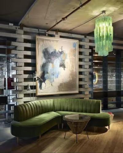 a green couch in a living room with a painting at Nishi Holiday Apartments in Canberra