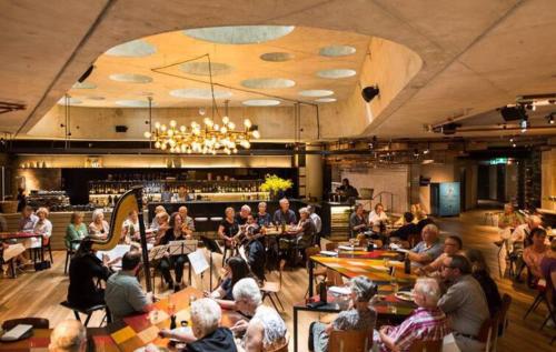 a group of people sitting at tables in a restaurant at Nishi Holiday Apartments in Canberra