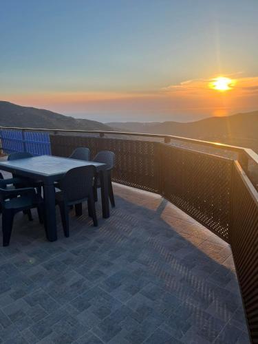 a balcony with a table and chairs and the sunset at Villa Art Natalie in Kithnos