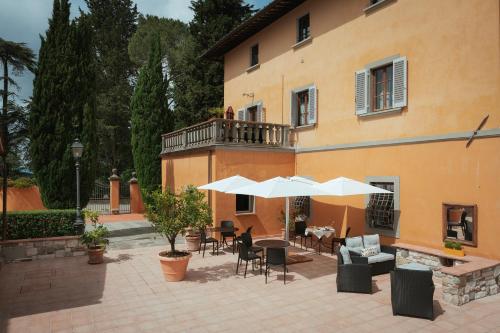 un patio con mesas y sombrillas frente a un edificio en Villa La Cappella, en Montespertoli