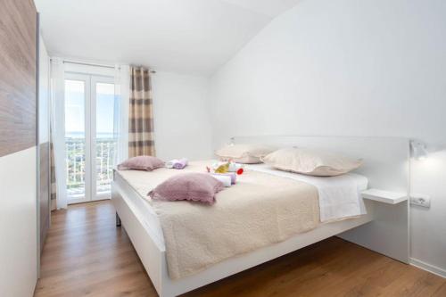 a white bedroom with a bed with pillows and a window at DELUX 2 bedrooms Apartment near SPLIT - GOGA in Žrnovnica