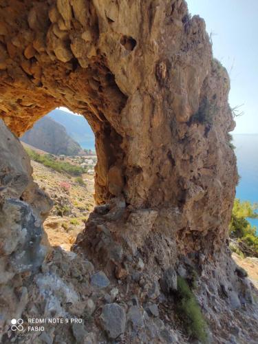 an arch in the side of a rocky mountain at Zorbas Studios in Agia Roumeli