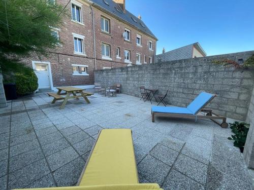 a patio with two benches and a table and a wall at l'albatros "le pont" in Cayeux-sur-Mer