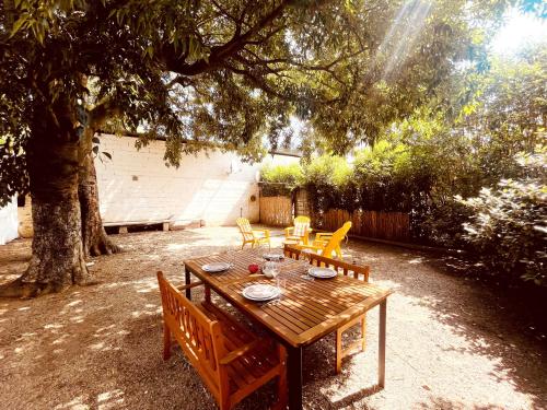 drewniany stół i krzesła pod drzewem w obiekcie Le patio, jardin privatif, tennis w mieście Nîmes