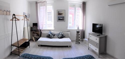 a white living room with a couch and a tv at Gîte Escale en vue - 3 Chambres - 150 m de la plage - in Fécamp