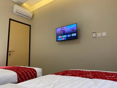 a room with two beds and a flat screen tv on the wall at Omah Soemantri 