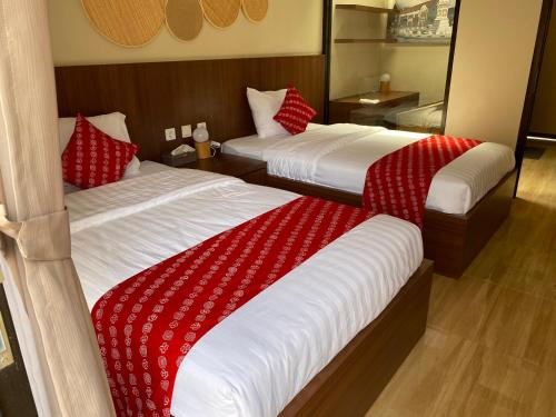 two beds in a hotel room with red and white blankets at Omah Soemantri 