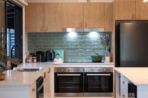 a kitchen with stainless steel appliances and a green tile wall at The House - The Charles at Broke Hunter Valley Luxury in Broke