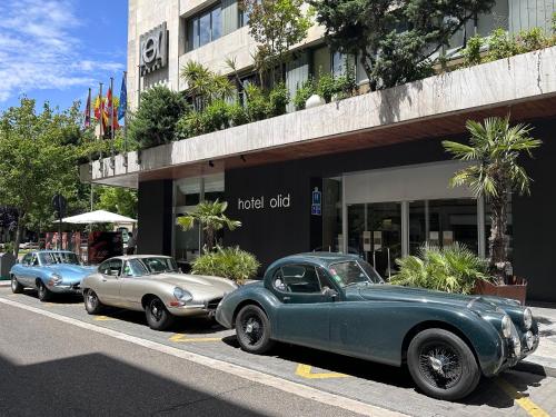 três carros velhos estacionados em frente a um edifício em Hotel Olid em Valladolid