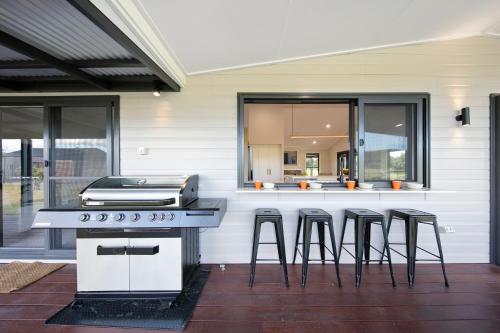 a backyard patio with a grill and bar stools at The House - The Charles at Broke Hunter Valley Luxury in Broke