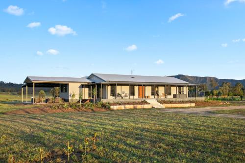 a house with a large field in front of it at The House - The Charles at Broke Hunter Valley Luxury in Broke