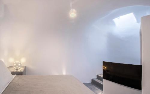 a bedroom with a bed and a flat screen tv at AQUA SERENITY LUXURY SUITES SANTORINI in Foinikiá