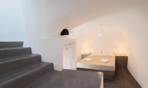 a small bedroom with a bed and a staircase at AQUA SERENITY LUXURY SUITES SANTORINI in Foinikiá