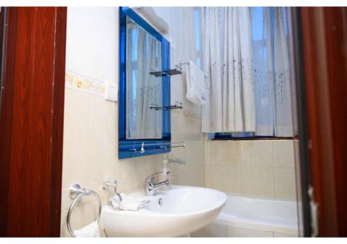 a bathroom with a sink and a mirror and a tub at White Stone Apartments in Kigali