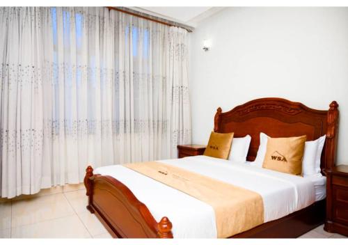 1 dormitorio con 1 cama grande y cortinas blancas en White Stone Apartments, en Kigali