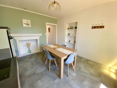 ein Esszimmer mit einem Holztisch und blauen Stühlen in der Unterkunft Maison Calme avec extérieur 