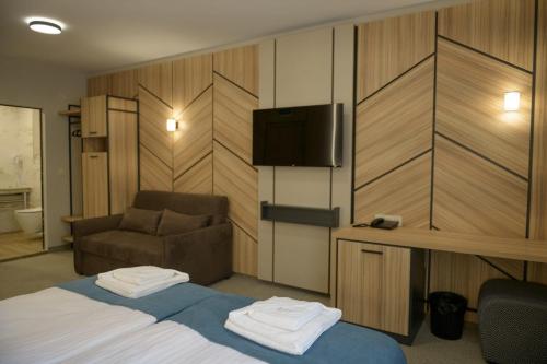 a hotel room with a bed and a couch and a television at Hotel Forum City in Pazardzhik