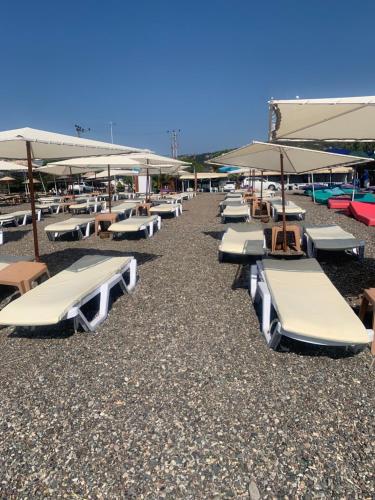 un grupo de tumbonas y sombrillas en una playa en Pina bungalov restaurant, en Ayvacık