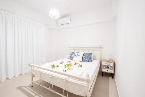 Ennea suites-Earth suite في Flámbouras: غرفة نوم بيضاء مع سرير أبيض عليه زهور