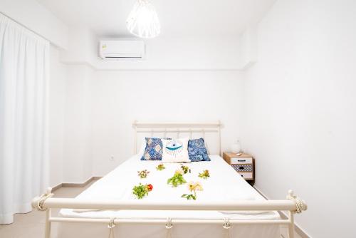 a white bedroom with a white bed with flowers on it at Ennea suites-Earth suite in Flámbouras