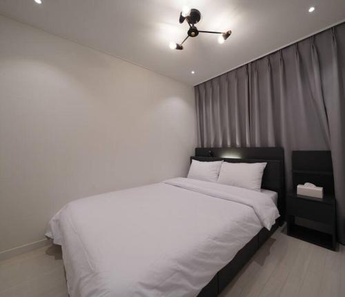 1 dormitorio con cama blanca y ventilador de techo en Dawn House, en Seúl