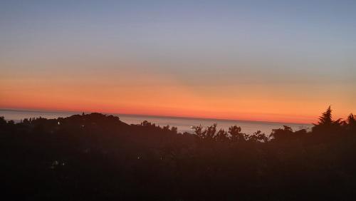 a sunset over the ocean with trees in the foreground at VILLA GANTIADI in Batumi