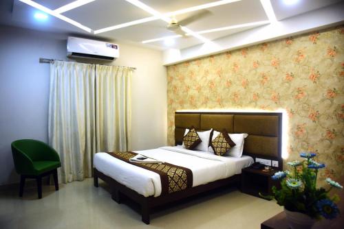 ein Schlafzimmer mit einem Bett und einem grünen Stuhl in der Unterkunft Pine Tree Signature in Chennai
