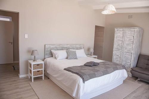 1 dormitorio con 1 cama grande y 1 silla en Bella Vista Yzerfontein - No loadshedding - Home away from home, en Yzerfontein