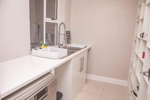 a white kitchen with a sink and a mirror at Bella Vista Yzerfontein - No loadshedding - Home away from home in Yzerfontein