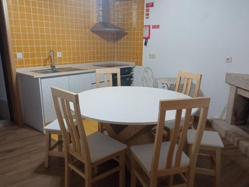 uma mesa branca e cadeiras numa cozinha com um lavatório em Casa Tia Vina - Serra em Arouca