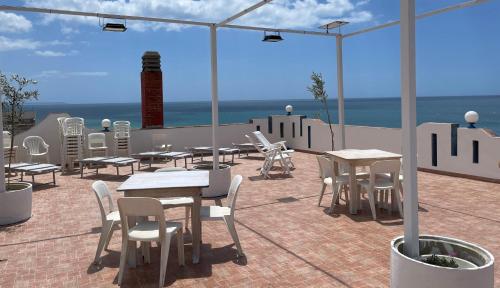 a patio with tables and chairs and a view of the ocean at Hotel Miramare Garzia in Marinella di Selinunte