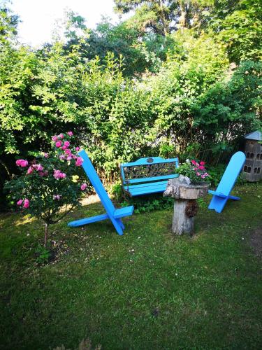 two blue chairs and a bench in a yard at Pension zum Sägebock in Berlin