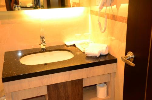 a bathroom with a sink and a phone at Nagoya Hill Hotel Batam in Nagoya