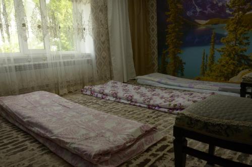 twee bedden in een kamer met een raam bij Woody Guest House Nursultan in Kaindy