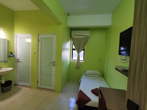 een groene kamer met een bed en een wastafel bij Walk Inn in Miri