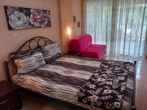 um quarto com uma cama e uma cadeira rosa em Sofia's house em Flogita