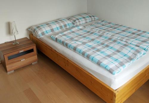a bed with a plaid comforter and a night stand at Ferienwohnung Schallinger in Teisendorf