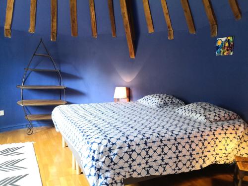 une chambre avec un lit avec un mur bleu dans l'établissement Gite La Tourelle Château de Montchevreau, à Cosne Cours sur Loire