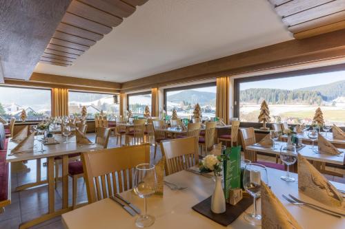 un restaurante con mesas y sillas con montañas al fondo en BSW Schwarzwaldhotel Baiersbronn en Baiersbronn