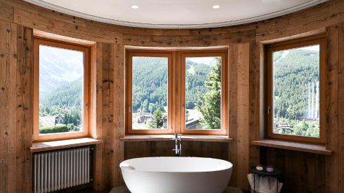 a bathroom with a white tub and three windows at Grey Castle garnì&suite in Ponte di Legno