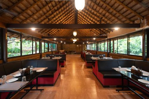 a dining room with tables and chairs and windows at Ibex River Resort, Pollachi in Coimbatore