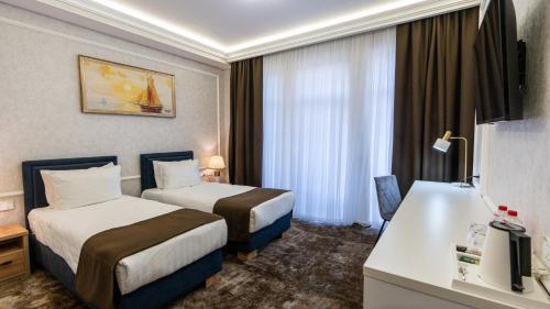 タシュケントにあるGarnet Mir Hotelのベッド2台とデスクが備わるホテルルームです。