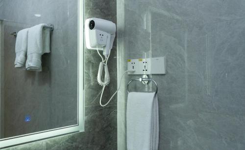 La salle de bains est pourvue d'une douche et d'un téléphone mural. dans l'établissement Garnet Mir Hotel, à Tachkent