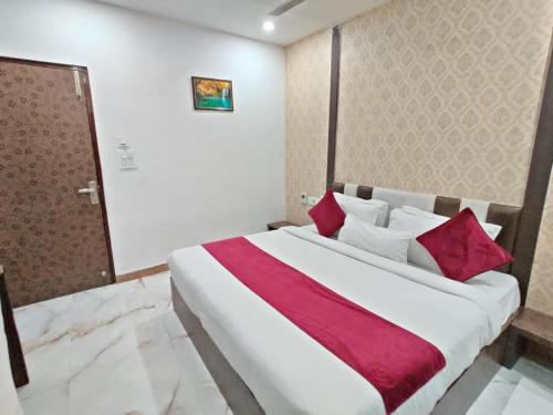 um quarto com uma grande cama branca com almofadas vermelhas em Flexi Hospitality - A Star - अमृतसर का सबसे Premium होटल em Amritsar