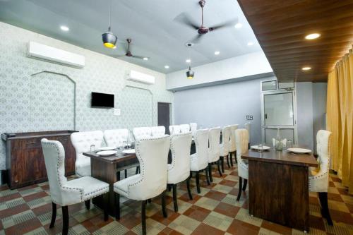 uma sala de jantar com uma mesa longa e cadeiras brancas em Flexi Hospitality - A Star - अमृतसर का सबसे Premium होटल em Amritsar